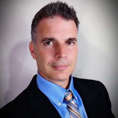 Dr. Derek Robertson - White Male with short brown hair wearing a blue button shirt orange, white and blue striped tie and sports coat.